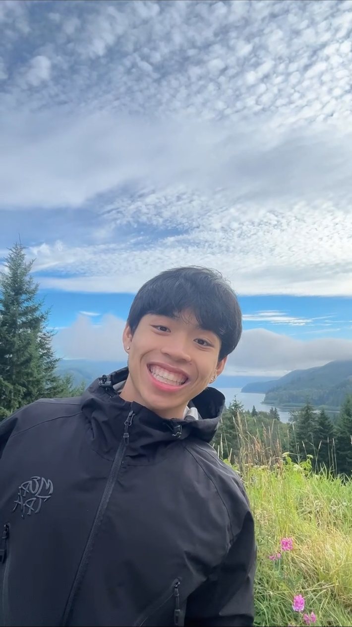 Huy smiling at a lookout above a river valley